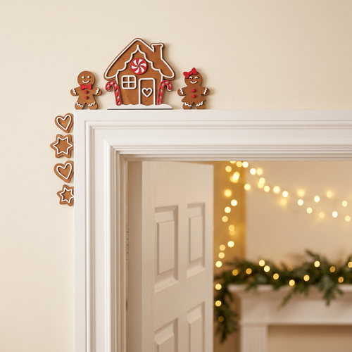 Laser cut wood gingerbread corner decoration mounted on top of white interior door frame in cozy Christmas home
